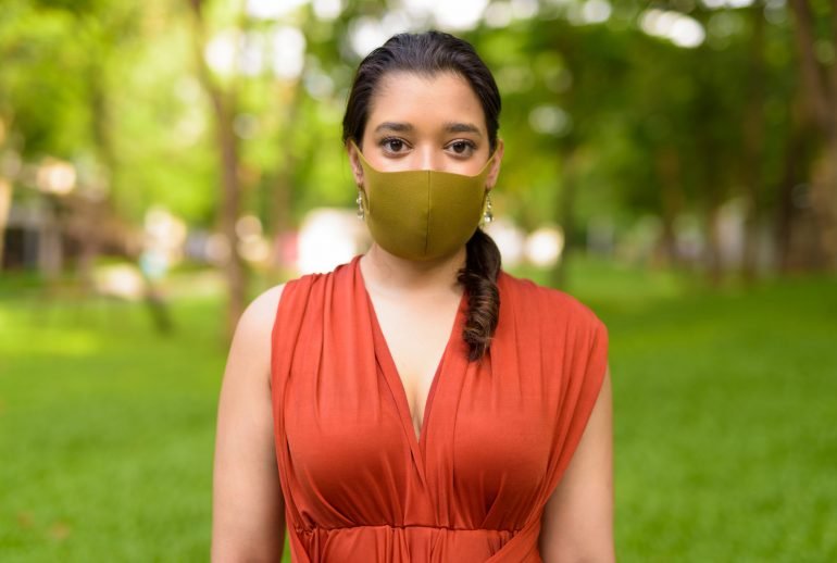 Portrait of young Indian woman with mask for protection from corona virus covid-19 outbreak at the park outdoors